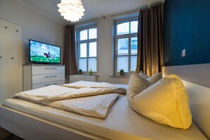Et hotelværelse med en seng, et fjernsyn, et vindue med gardiner og havudsigt.