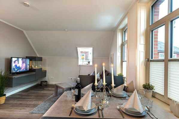Una sala de estar moderna con televisor, mesa de comedor para cuatro personas y chimenea.