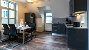 A modern kitchen with a dining area, featuring a table set for two, a microwave, and a coffee machine. - Altstadt Borkum Apartment 4 Bant - Altstadt Villa Borkum (Borkum)
