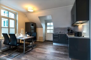 Une cuisine moderne avec un coin repas, comprenant une table dressée pour deux personnes, un four à micro-ondes et une machine à café.