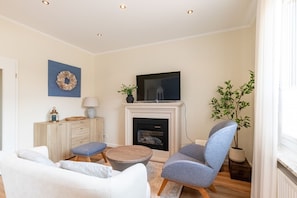 A living room with a fireplace, a television, a sofa, a chair, and a small table.