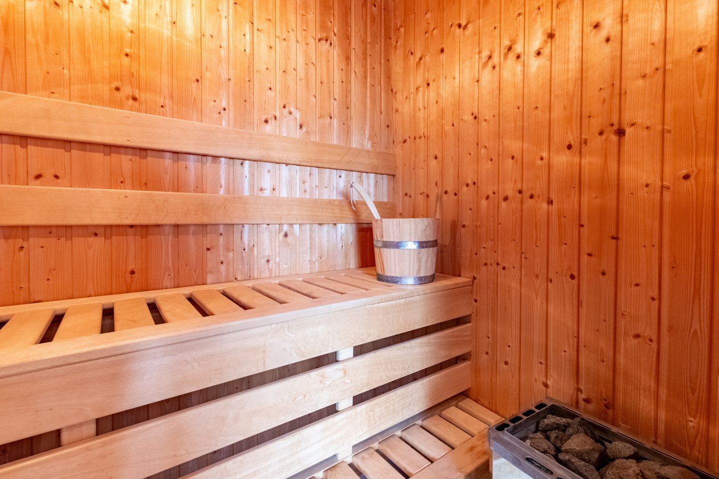 A wooden sauna with benches and a bucket.
