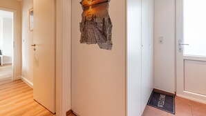 En gang med en dør, en velkomst måtte og en væg med en struktureret kunstinstallation.