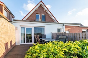 A house with a red brick facade, a white upper section, and a wooden deck.