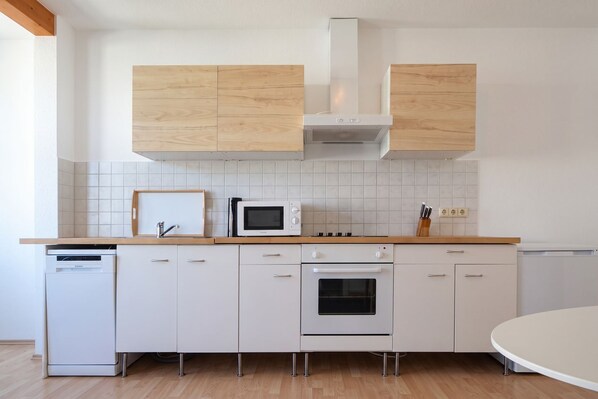 Una cocina moderna con armarios blancos, microondas, horno y lavavajillas.