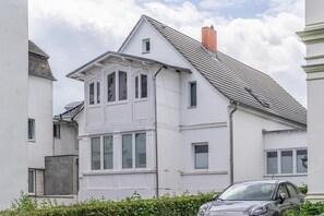 Un edificio residencial de dos pisos con techo a dos aguas, varias ventanas y una chimenea visible.