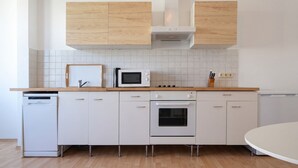 A modern kitchen with white cabinetry, a microwave, an oven, and a dishwasher.