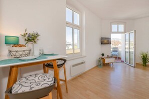 A modern apartment with a dining area, a living room with a TV, and a balcony with a view. - Apartment Karlskrona in Ahlbeck with balcony, close to the beach - Haus Skanska (Heringsdorf)