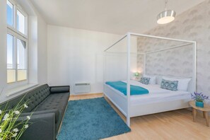 Une chambre à coucher avec un lit à baldaquin, un canapé, une petite table ronde et une fenêtre.