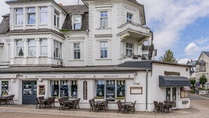 A multi-story building with a ground-floor restaurant featuring outdoor seating. - Apartment Karlskrona in Ahlbeck with balcony, close to the beach - Haus Skanska (Heringsdorf)