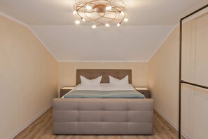 Ein Schlafzimmer mit einem Bett, einem Nachttisch, einer modernen Kronleuchter und Holzboden.