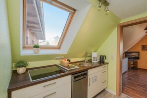 Una cocina con tragaluz, un lavabo, una cafetera y un televisor en la habitación contigua.