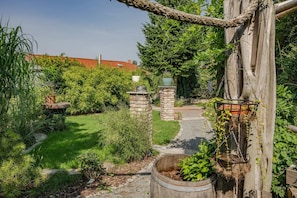 A garden with a stone pathway, a wooden trellis, and various plants. - Cozy vacation apartment in Heringsdorf with garden, only 550 m from the beach (Heringsdorf)