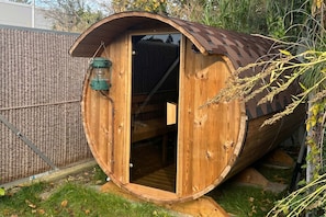 A wooden barrel-shaped structure with a door, a hanging lantern, and a small window. - Cozy vacation apartment in Heringsdorf with garden, only 550 m from the beach (Heringsdorf)