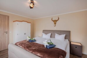 Ein Schlafzimmer mit einem Bett, einem Nachttisch, einem Kleiderschrank und einer Wanddekoration mit einem Stierkopf.