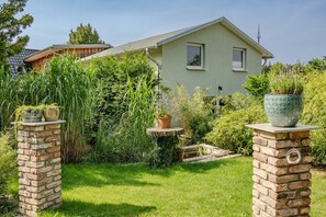 A house with a green exterior, a brick garden wall, and potted plants on top.