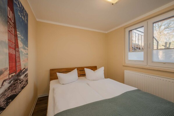 A bedroom with a bed, a window, and a poster on the wall.