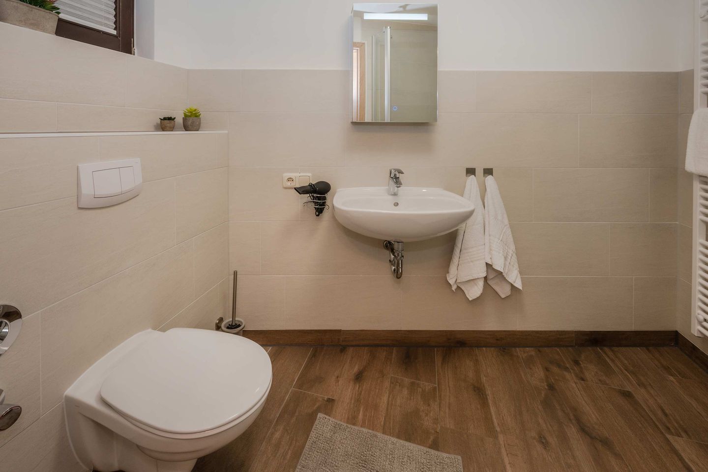 Une salle de bain équipée de toilettes, d’un lavabo, d’un miroir et de serviettes.