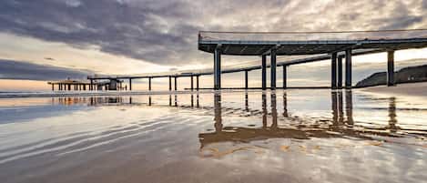 Un muelle se adentra en aguas tranquilas bajo un cielo nublado.