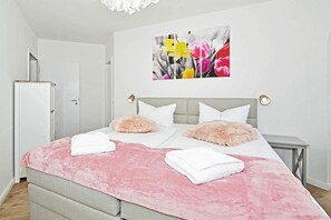 A hotel room with a bed, two bedside tables, a wardrobe, and a painting on the wall.