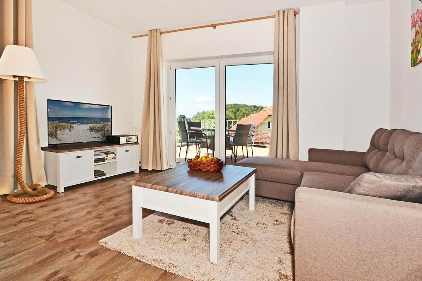 Una sala de estar con televisor, sof á, mesa de centro y vistas al exterior.