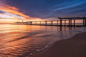 A pier extending into calm waters with a sunset in the background.