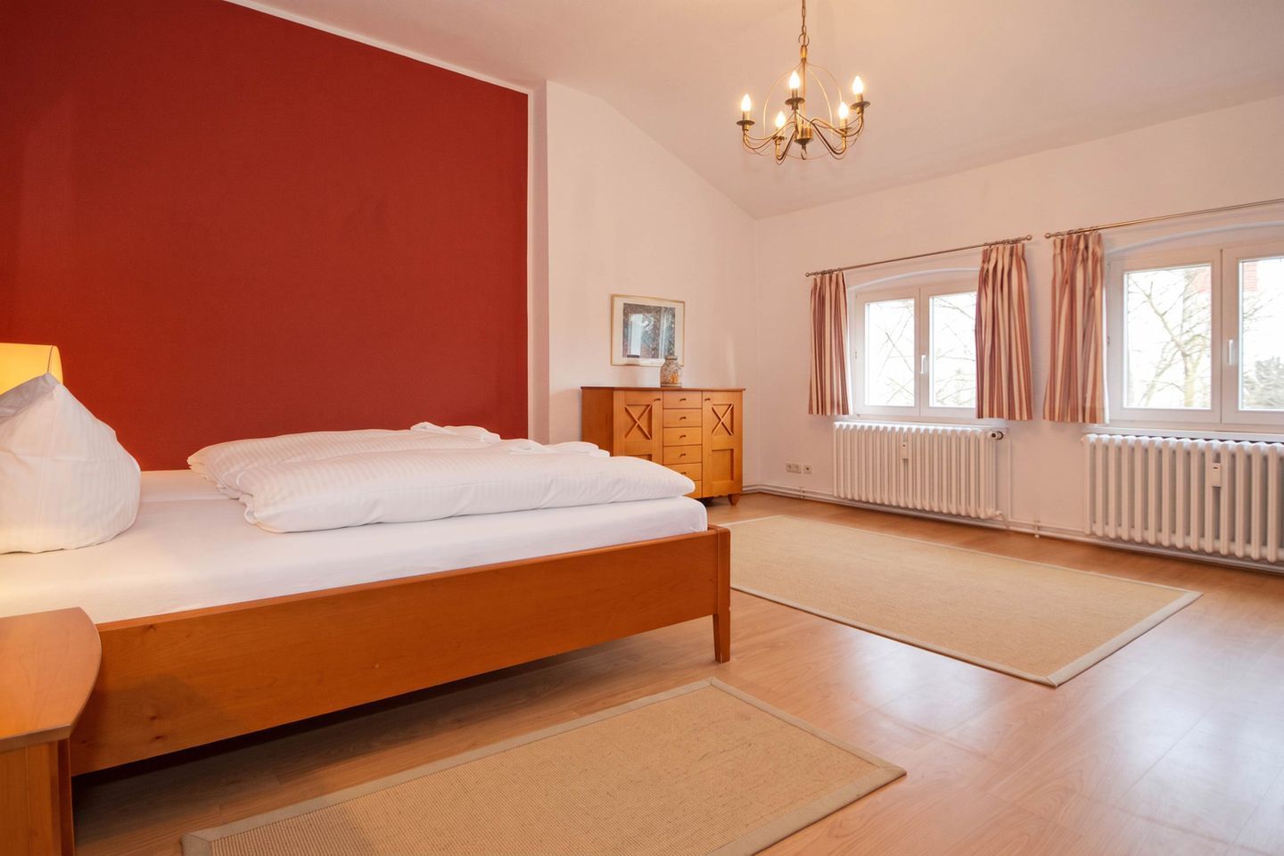 A bedroom with a bed, wooden dresser, and a radiator.
