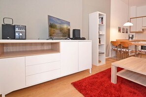 A modern kitchen with white cabinetry, a red rug, and a dining area with wooden chairs. - Charming vacation apartment in Heringsdorf with balcony, only 200 m from the Baltic Sea beach - (Heringsdorf)