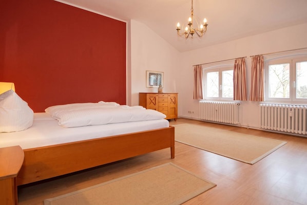 A bedroom with a bed, wooden dresser, and a radiator.