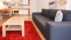 A modern living room with a grey sofa, a wooden coffee table, and a red rug.