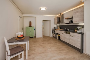 Eine moderne Küche mit Essbereich, mit hellem Holzfußboden, einem grünen Schrank und einem eingebauten Backofen.