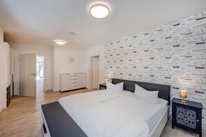 A bedroom with a bed, bedside tables, a wardrobe, and a wall with a nautical pattern.