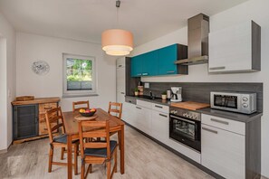 A compact kitchen with a dining table, chairs, a microwave, a coffee maker, and cabinets.