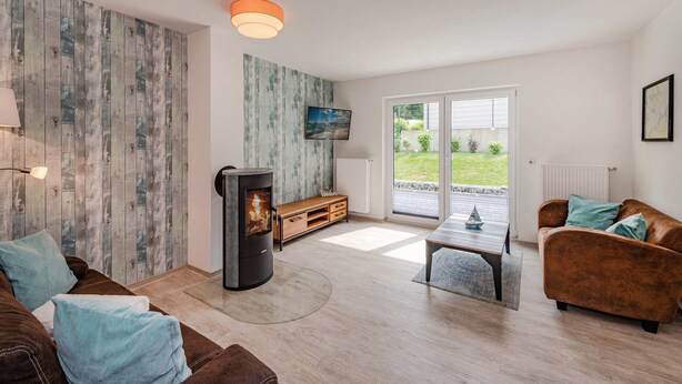 A modern living room with a fireplace, a television, and a view of the outdoors. - Modern vacation apartment in Heringsdorf with terrace, only 1000 m from the beach (Heringsdorf)