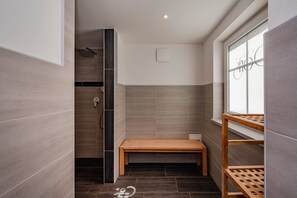 A modern bathroom with a shower, a bench, and a window.