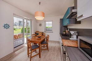 Een moderne keuken met een eethoek, een groot raam en uitzicht op de omgeving.