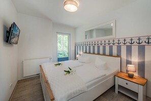 Una camera da letto con un letto, un comodino, una televisione appesa al muro.