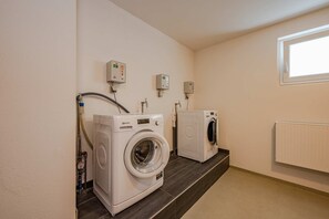 Une buanderie équipée de deux machines à laver, d’un radiateur et d’une fenêtre.