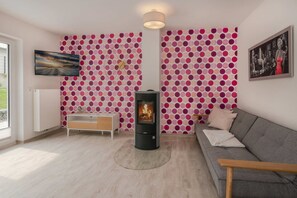 A living room with a fireplace, a sofa, a TV, and a polka dot wallpaper.