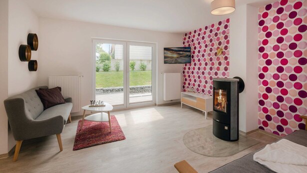 A modern living room with a sofa, a small table, a TV, and a fireplace.