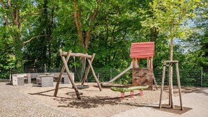 Un parque infantil con columpios, tobogán y estructura para escalar.