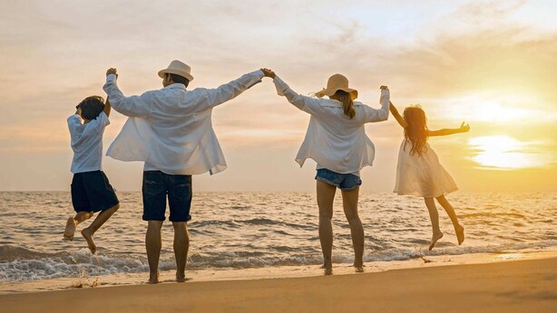 Una familia de cuatro personas en la playa durante el atardecer.