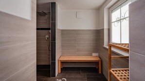 Un baño moderno con ducha, una banca y una ventana.