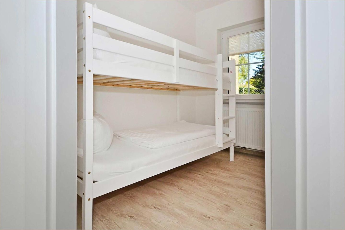 Ein Stockbett in einem Zimmer mit Holzdielen und einem Fenster.