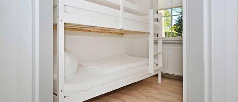 Ein Stockbett in einem Zimmer mit Holzdielen und einem Fenster.