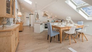 Une cuisine moderne avec un coin repas, des fenêtres de toit et une vue sur le ciel.