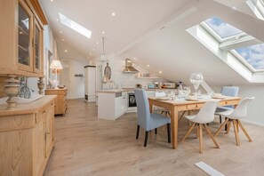 A modern kitchen with a dining area, skylights, and a view of the sky.