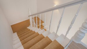 Un escalier avec des balustrades blanches et un luminaire fixé au mur.