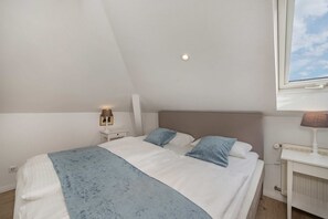 Ein Schlafzimmer mit einem Bett, Nachttischen, Lampen und einem Fenster.