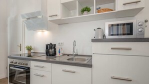 Une cuisine moderne équipée d’un four encastré, d’un four à micro-ondes, d’une machine à café et d’un évier.